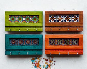 May include: Four colorful key holders with decorative ceramic tiles. Each holder has a rectangular wooden frame in green, brown, teal, and orange. The tiles feature floral patterns in various colors. Each holder has five metal hooks.