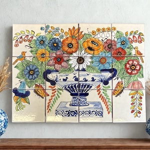 May include: A twelve-tile mural featuring a hand-painted floral arrangement in a blue and white urn, surrounded by butterflies and birds. The design includes vibrant orange, red, and blue flowers on a cream background, flanked by two blue and white vases.