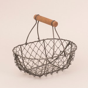 Könnte beinhalten: Ein grauer Drahtkorb mit einem Holzgriff. Der Korb ist oval geformt und hat ein Drahtgeflecht-Design.