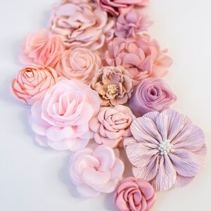 Puede incluir: Una colecci&oacute;n de flores de tela rosa y rubor, dispuestas en un patr&oacute;n en cascada. Las flores est&aacute;n hechas de varios materiales, incluyendo seda y sat&eacute;n, y tienen un aspecto delicado y femenino.