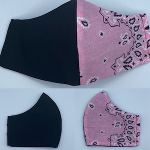May include: A black and pink face mask with a bandana pattern. The mask is made of two layers of fabric, with the top layer being black and the bottom layer being pink with a black bandana pattern.