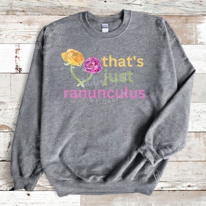 May include: Gray sweatshirt with a pink and yellow flower graphic and the text "that's just ranunculus".