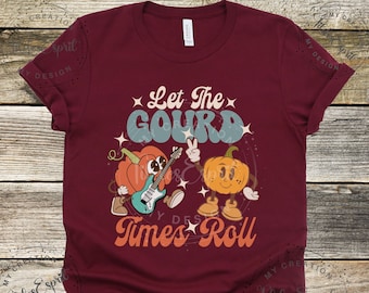 May include: A maroon t-shirt featuring a graphic of two cartoon pumpkins. One pumpkin is playing a guitar and the other is holding a peace sign. The text "Let the Gourd Times Roll" is printed on the shirt.
