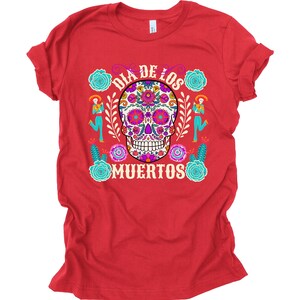 May include: Red t-shirt with a colorful sugar skull design and the text "Dia de los Muertos".
