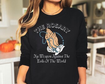 May include: Black sweatshirt with a graphic of praying hands holding a rosary with the text "The Rosary My Weapon Against The Evils Of The World"