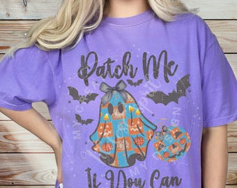 May include: A purple t-shirt with the text "Patch Me If You Can". The shirt features a graphic of a ghost with a bow, pumpkins, and bats, perfect for Halloween.