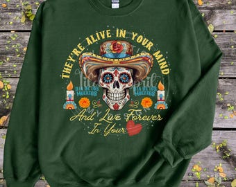 May include: Green sweatshirt with a colorful sugar skull graphic and the text "They're alive in your mind and live forever in your"