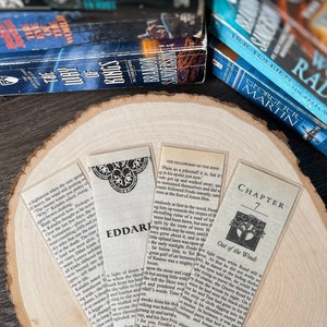 May include: Three bookmarks with different designs. The first bookmark features a black and white illustration of a tree with a quote from "The Fellowship of the Ring" by J.R.R. Tolkien. The second bookmark features a black and white illustration of a tree with the text "Eddard" at the top. The third bookmark features a black and white illustration of a tree with the text "Chapter 7 Out of the Woods" at the top.
