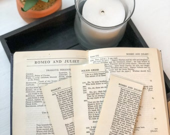 May include: A close-up of a vintage book open to a page with the title "Romeo and Juliet". The book is worn and has yellowed pages. There are several bookmarks sticking out of the book, including one with the title "Hamlet".