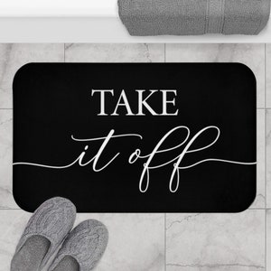 May include: Black bath mat with white text that reads "TAKE it off".
