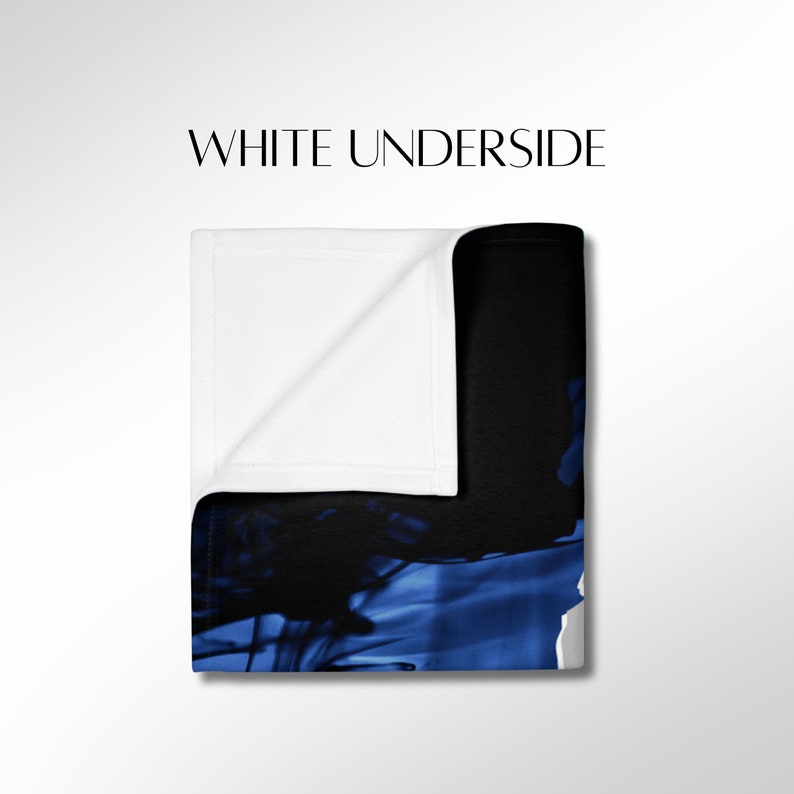 May include: A soft, blue and black fleece blanket with a white underside. The blanket is folded in half, showing the white underside.