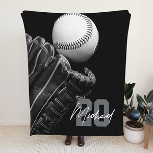 May include: Black and white baseball themed fleece blanket featuring a baseball glove, baseball, and the number 20 with the name Michael in a script font.