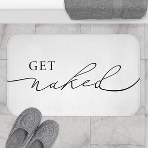 May include: White bath mat with black text that reads "GET naked" in a cursive font.