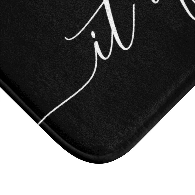 May include: Black bath mat with white cursive text that reads "it is well".
