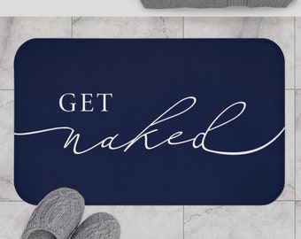 May include: A navy blue bath mat with white text that reads "GET naked" in a cursive font.