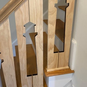 May include: A wooden staircase railing with a unique design featuring cutouts of lighthouses. The railing is made of light-colored wood and the cutouts are painted black.