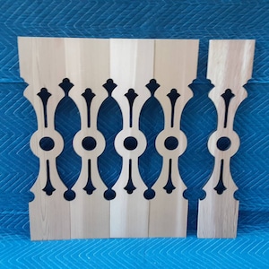 May include: Five unfinished wooden spindles with a decorative cut-out design. The spindles are arranged in a row on a blue surface.