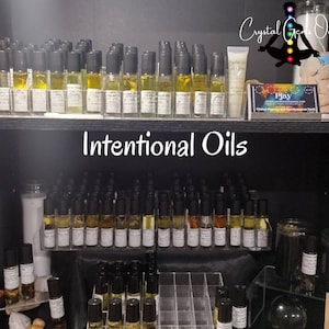 Puede incluir: Un estante de exhibici&oacute;n con peque&ntilde;as botellas de vidrio llenas de l&iacute;quido amarillo, etiquetadas como "Intentional Oils". Las botellas est&aacute;n dispuestas en filas en un estante negro. Las botellas son todas del mismo tama&ntilde;o y forma, y tienen tapas negras. El estante est&aacute; en una tienda con otros art&iacute;culos en exhibici&oacute;n.