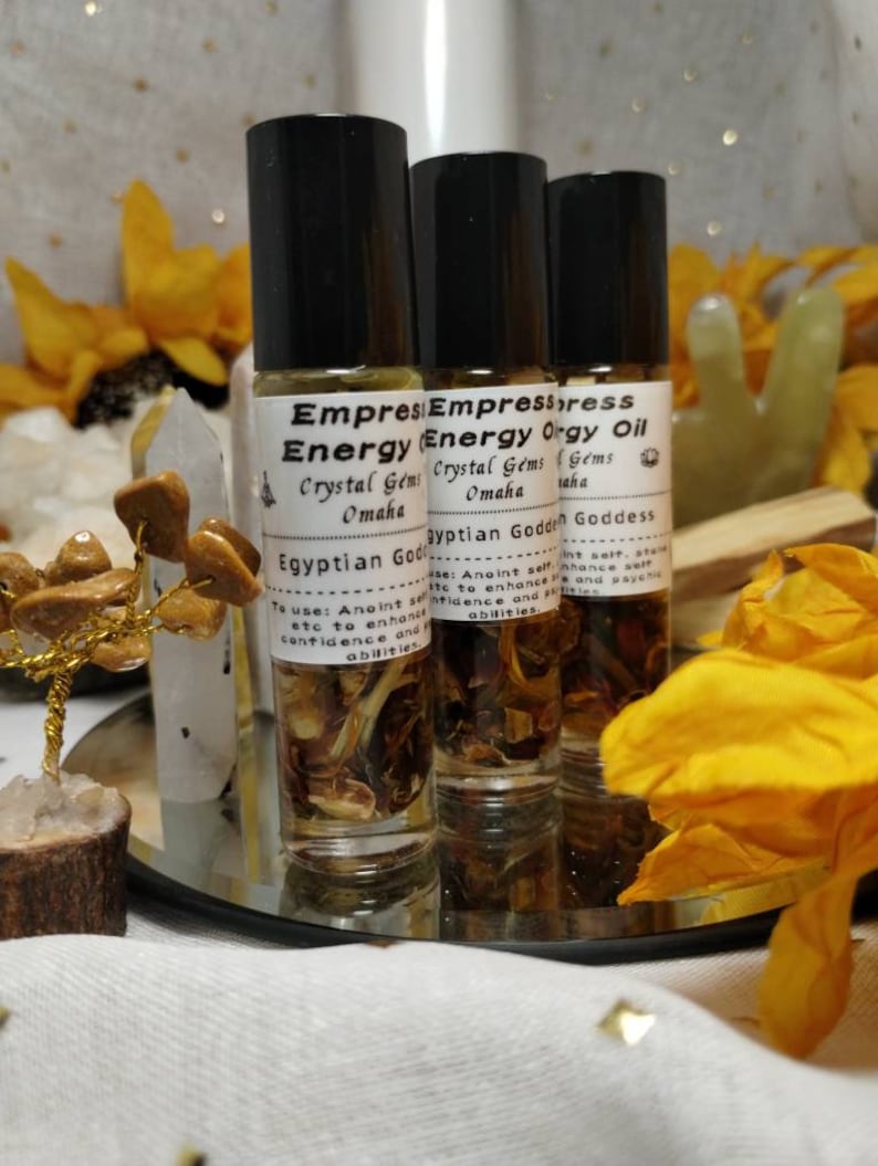 Puede incluir: Tres peque&ntilde;os frascos de vidrio con tapas de rodillo llenos de un l&iacute;quido marr&oacute;n. Los frascos est&aacute;n etiquetados con "Empress Energy Oil" con el texto "Crystal Gems Omaha" y "Egyptian Goddess".