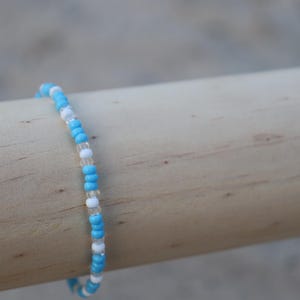 May include: A blue and white beaded bracelet with a simple design.