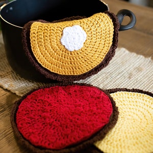 May include: Three crocheted pot holders, one yellow with a white center, one red, and one yellow. All have brown trim.