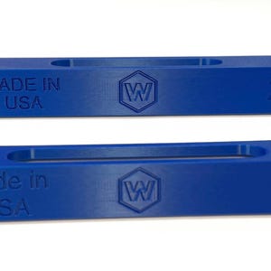 May include: Two blue rectangular objects with a recessed center. The text "MADE IN USA" is visible on each, along with a hexagonal logo and the numbers "1" and "2".