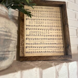 K&ouml;nnte beinhalten: Ein gerahmter Druck eines alten Kirchenliedblattes mit dem Titel "Great is Thy Faithfulness". Die Notenbl&auml;tter enthalten den Text und die Noten des Kirchenliedes.