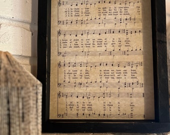 May include: A framed sheet of music with the title "In Christ Alone" and lyrics printed in black ink on a white background. The music is written in a traditional style with notes and clefs.