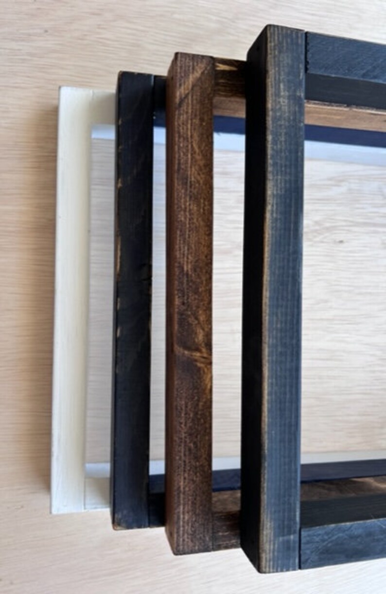 May include: Three wooden picture frames in different sizes and colors. The largest frame is black, the middle frame is brown, and the smallest frame is white.