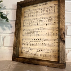 Puede incluir: Una impresi&oacute;n de partitura vintage enmarcada con el t&iacute;tulo "Sweet By and By" y letras de la canci&oacute;n. La partitura est&aacute; impresa en papel envejecido con un fondo marr&oacute;n y notas musicales negras.