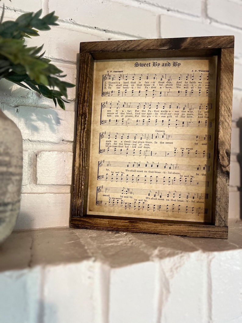 Puede incluir: Una impresi&oacute;n de partitura vintage enmarcada con el t&iacute;tulo "Sweet By and By" y la letra de la canci&oacute;n. La partitura est&aacute; impresa en papel envejecido con un fondo marr&oacute;n y notas musicales negras.
