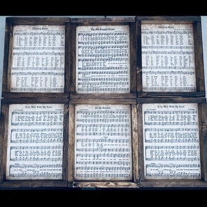 Puede incluir: Seis impresiones enmarcadas de partituras musicales antiguas con letras y notaci&oacute;n musical. Los t&iacute;tulos de las canciones son "Amazing Grace", "The Old Rugged Cross", "In The Garden", y "It Is Well With My Soul". Los marcos son de madera r&uacute;stica.