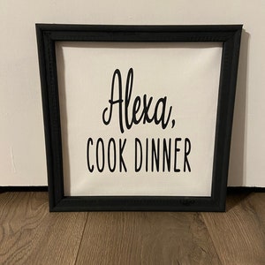 May include: A black framed canvas sign with white text that reads "Alexa, cook dinner".