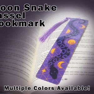 May include: Purple and gold bookmark featuring a snake design with moons and stars. The bookmark has a purple tassel.