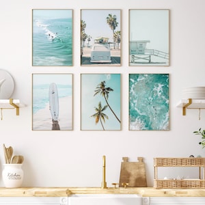 May include: A set of six framed prints featuring beach scenes. The prints include a surfboard, a vintage van, palm trees, and ocean waves. The prints are all in a light blue and white color scheme.