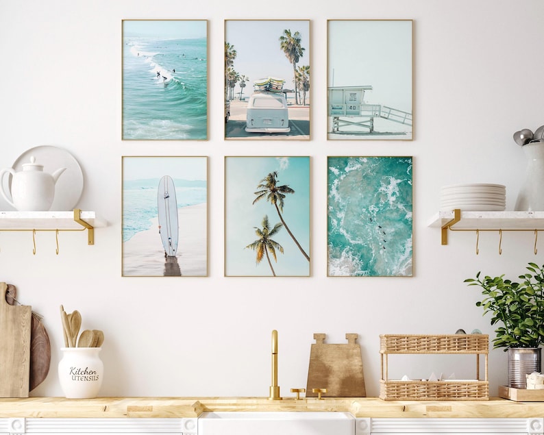 May include: A set of six framed prints featuring beach scenes. The prints include a surfboard, a vintage van, palm trees, and ocean waves. The prints are all in a light blue and white color scheme.