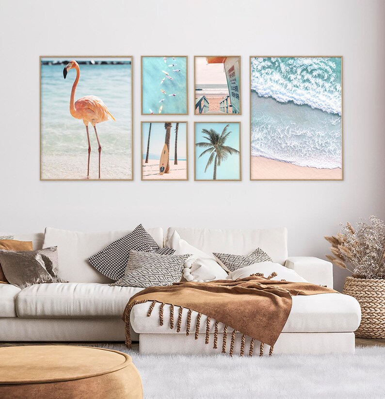 May include: A collage of six framed photographs featuring beach scenes. The top left photo shows a pink flamingo standing in shallow water. The top middle photo shows a group of people paddleboarding in turquoise water. The top right photo shows a view of a beach with a lifeguard stand. The bottom left photo shows a surfboard leaning against a palm tree. The bottom middle photo shows a palm tree with blue sky in the background. The bottom right photo shows a close-up of ocean waves crashing on a sandy beach.