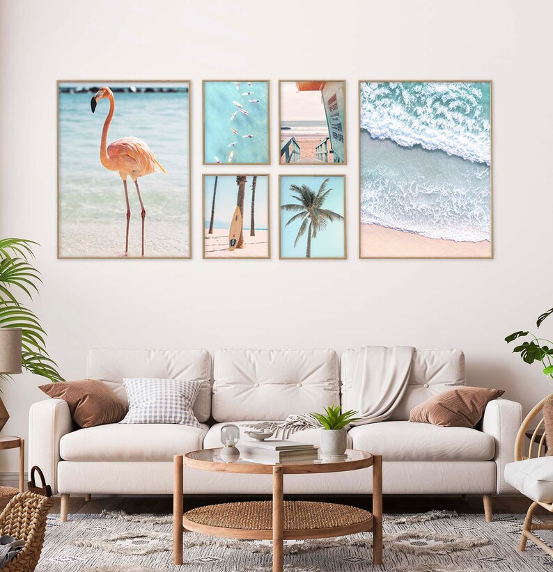 May include: A set of six framed prints featuring beach scenes. The prints include a pink flamingo standing in the water, a palm tree, a surfboard, a group of people swimming in the ocean, a lifeguard stand, and a wave crashing on the shore.