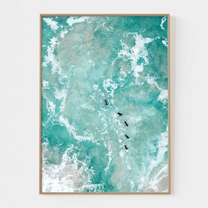 May include: An aerial view of turquoise ocean water with white foamy waves. Five people are swimming in the water, facing the camera.