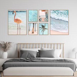 May include: A set of six framed prints featuring beach scenes. The prints include a pink flamingo standing in the water, a palm tree, a surfboard, a view of the ocean from above, a view of the ocean from the beach, and a view of a boardwalk leading to the beach.