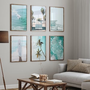 May include: A set of six framed prints featuring beach scenes. The prints include a surfboard on the beach, palm trees, a vintage van, and ocean waves. The prints are all in a light blue and green color scheme.