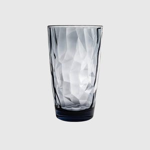 May include: A tall, cylindrical drinking glass made of translucent, smoky gray glass. The exterior surface features a faceted, geometric texture with numerous angular planes that catch the light, creating a complex, multi-faceted appearance.