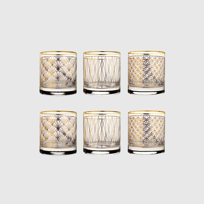 Puede incluir: Un juego de seis vasos de cristal transparente con patrones geom&eacute;tricos dorados. Cada vaso tiene un borde dorado y un dise&ntilde;o distintivo, incluyendo motivos en forma de abanico, l&iacute;neas verticales que se cruzan y patrones de rejilla circular.