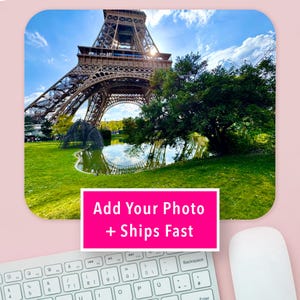 May include: A rectangular mouse pad featuring a photograph of the Eiffel Tower in Paris, France, with a green lawn, a pond, and trees. A bright pink rectangular overlay in the center displays the white text: Add Your Photo + Ships Fast.
