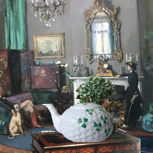 Puede incluir: Una tetera blanca con un diseño de cesta tejida y acentos de tréboles verdes. La tetera tiene un pico curvo y un asa. La tetera está sobre una mesa de madera en una habitación con una pintura y una persona.