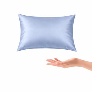 May include: A light blue satin pillow against a white background. The rectangular pillow is smooth and shiny. A hand is reaching up towards the pillow.
