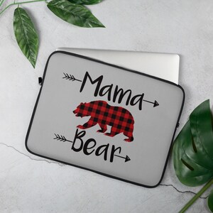 May include: Gray laptop sleeve with a red and black buffalo plaid bear and the text "Mama Bear" with arrows on either side.