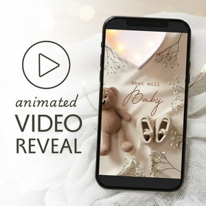 以下が含まれることがあります： スマートフォンは、アニメーションビデオの公開を表示します。ビデオには、テディベア、ベビーシューズ、テキスト「What will Baby」が表示されます。背景には花のアクセントと柔らかな照明があり、ベビー発表に最適です。