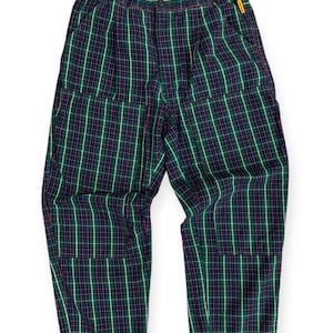 May include: Green, pink and white plaid trousers with a drawstring waist and two large pockets on the front.