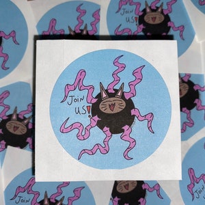 May include: A round sticker with a blue background and a black cat with pink tentacles. The cat has a smiling face and the text "Join Us!" is written in pink.